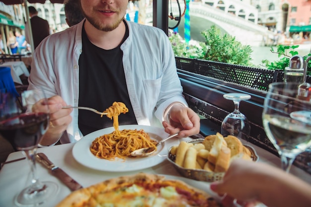 Mann sitzt im Café, isst Pasta, trinkt Wein, Rialto-Brücke, im Hintergrund, Venedig, Italien, Restaurant im Freien