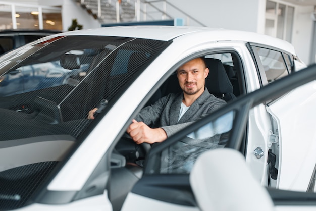 Mann sitzt im neuen Auto, Ausstellungsraum