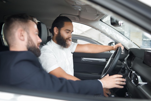 Mann sitzt in Autokabine mit Autohändler