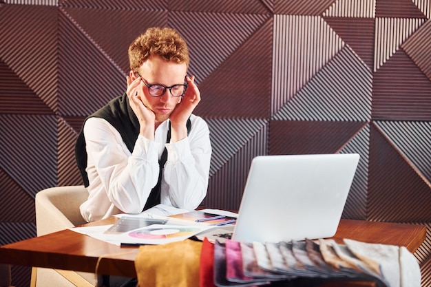 Mann sitzt mit Laptop am Tisch Innenbereich des neuen modernen Luxusrestaurants