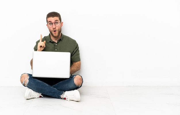 Mann sitzt mit Laptop auf dem Boden