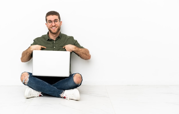 Mann sitzt mit Laptop auf dem Boden