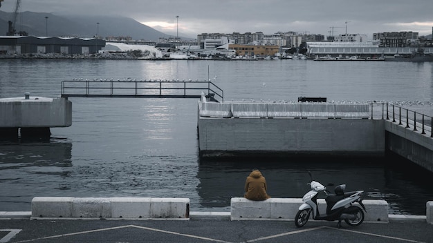 Mann sitzt mit Motorrad im Hafen