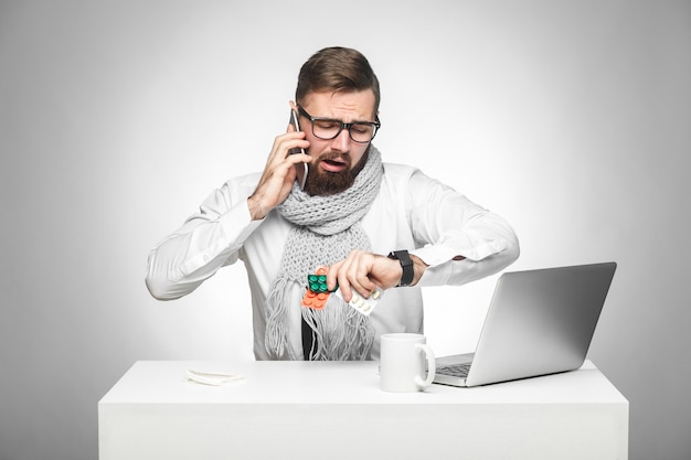 Mann sitzt und spricht mit dem Partner am Telefon und überprüft auch die Zeit auf seiner eigenen Handuhr