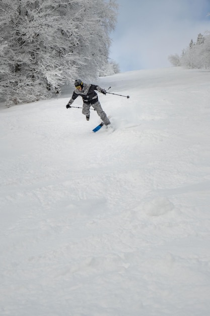 Mann-Skifahrer, der die Krankenversicherung herunterfällt