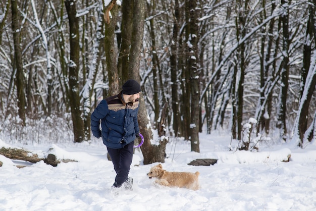 Mann spielen mit Hund im Schneewald