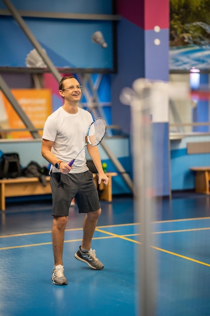 Mann spielt Badminton in Sportbekleidung auf dem Hallenplatz