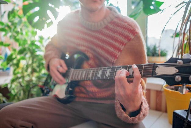 Mann spielt E-Gitarre an seinem Lieblingsplatz zwischen grünen Pflanzen. Persönliche Komfortzone