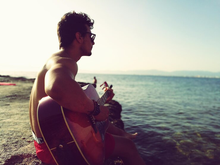 Foto mann spielt gitarre am meer