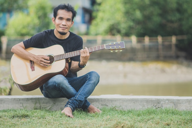 Mann spielt Gitarre im Freien glücklich im Sommer