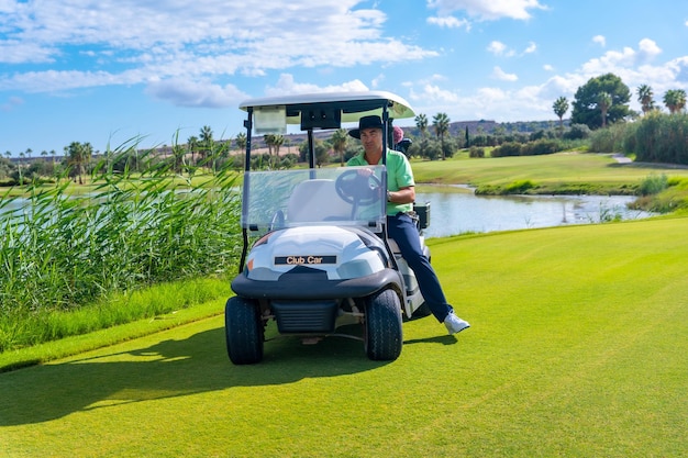 Mann spielt Golf im Buggy-Auto, das sich auf dem Golfplatz bewegt