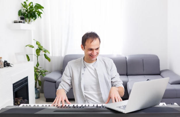 Mann spielt Musik mit Klavier und Laptop