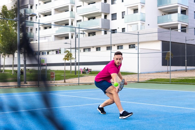 Mann spielt Pickleball-Spiel und schlägt Pickleball-Ball mit Paddel. Outdoor-Sport-Freizeitaktivität