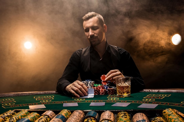 Mann spielt Poker mit einer Zigarre und einem Whisky ein Mann gewinnt alle Chips auf dem Tisch mit dickem ...