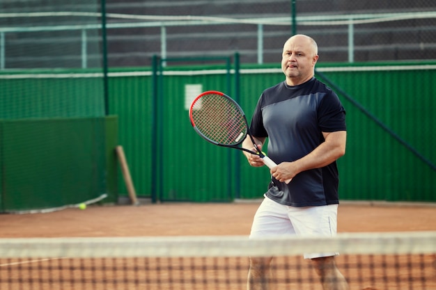 Mann spielt Tennis auf dem Platz. Aktiver Lebensstil und Gesundheit.