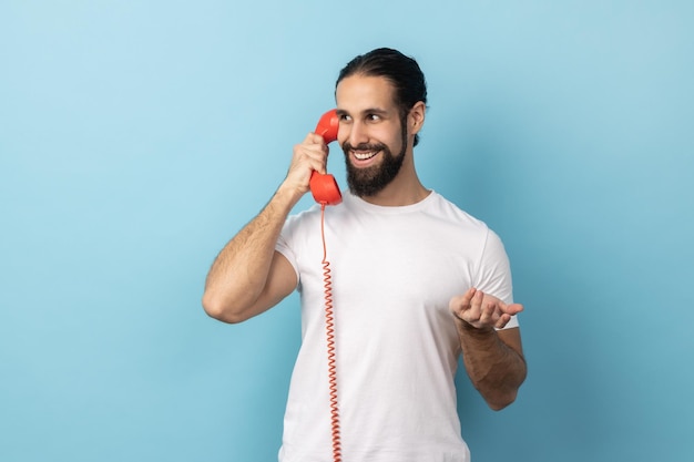 Mann spricht auf rotem Retro-Telefon und hat ein angenehmes Gespräch, das mit einem Lächeln wegschaut