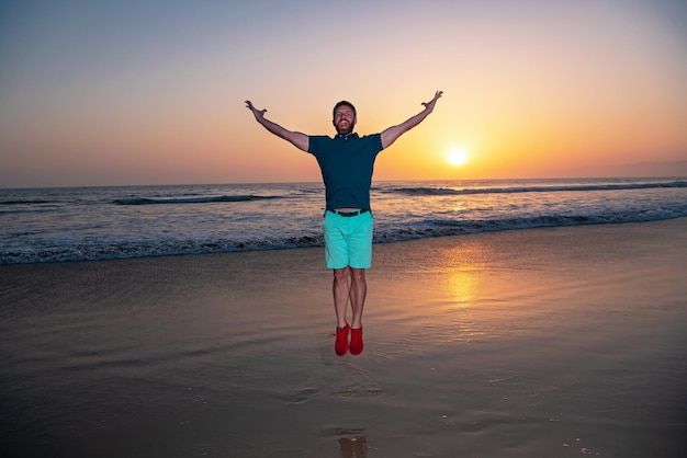 Mann springt am Strand, Silhouette im Sonnenuntergang. Erstaunliche Aussicht auf den Sonnenuntergangsstrand.