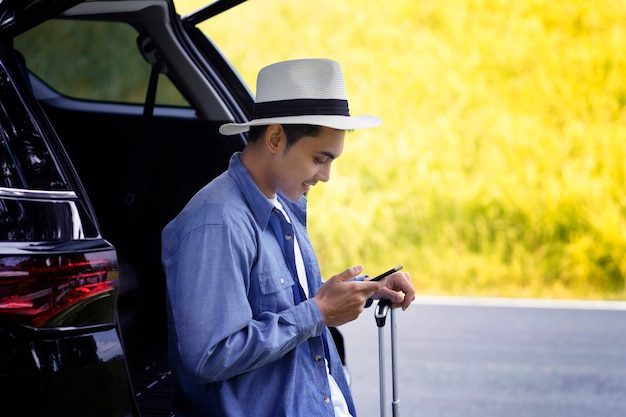 Foto mann stand mit handy und gepäck im auto