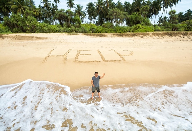 Mann steckt auf unbewohnter Insel mit Inschrift HILFE auf Sand fest