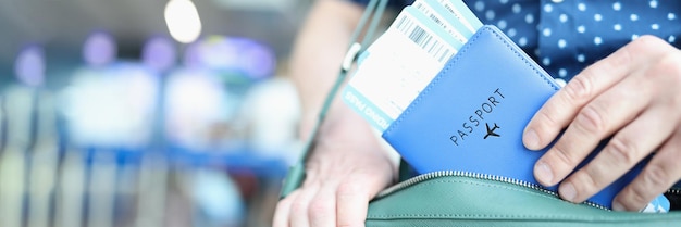 Mann steckt Reisepass mit Flugtickets in Laptoptasche Nahaufnahme