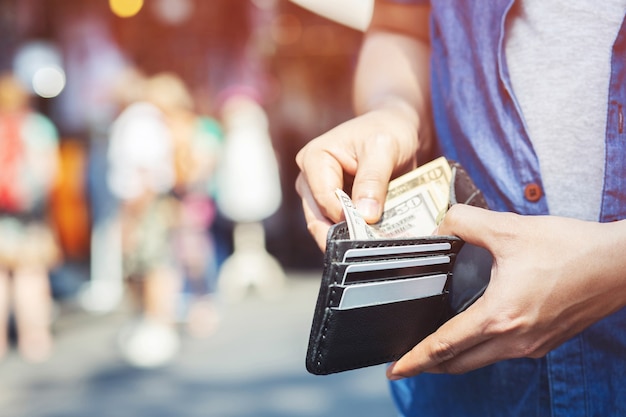 Mann stehend, der schwarze Brieftasche voll Geld hält