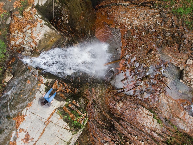 Mann steht auf der Klippe und blickt auf die Herbstzeit des Wasserfalls