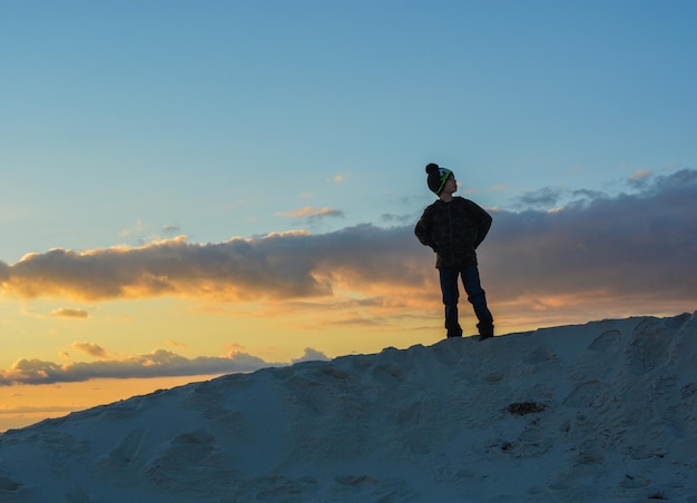 Mann steht auf einem schneebedeckten Berg gegen den Himmel beim Sonnenuntergang