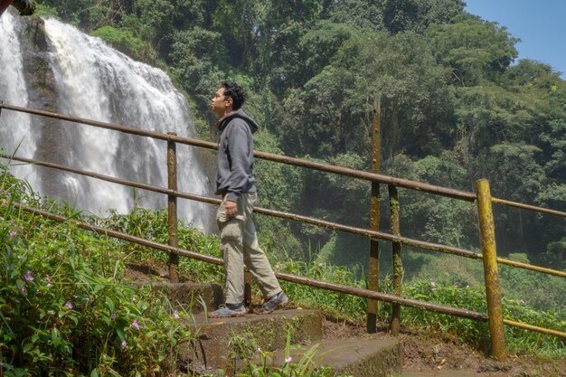 Mann steht mit Kapuzenpullover vor dem großen Wasserfall mit Handrolle Semarang Zentral-Java