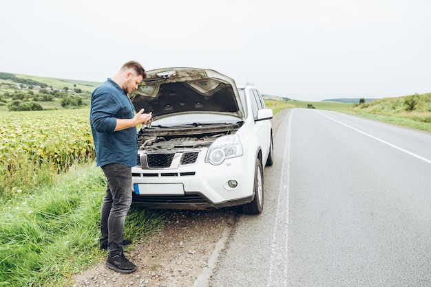 Mann steht vor kaputtem Auto