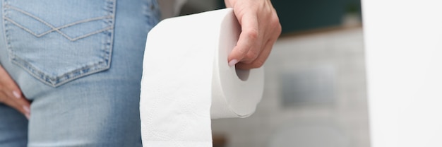 Mann steht vor Toilette und hält Toilettenpapier