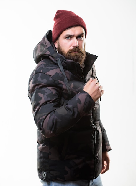 Foto mann steht warme tarnungsmuster jacke parka mit kapuze isoliert auf weißem hintergrund hipster winter mode winter stilvolle herrenbekleidung komfortable winter outfit mann trägt hut und schwarze winterjacke