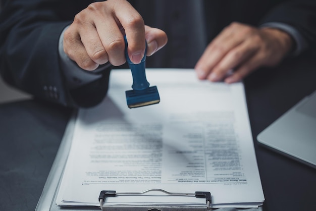 Foto mann stempelt die genehmigung von arbeitsfinanzierungs-banking- oder investment-marketing-dokumenten auf dem schreibtisch