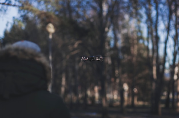 Mann steuert einen Quadrocopter. Selektiver Fokus auf Drohne, Männer sind verschwommen