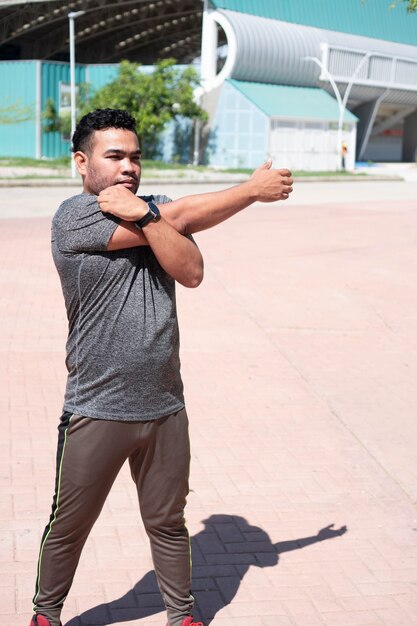 Mann streckt seinen Arm und wärmt sich für das Training auf.