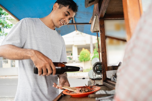 Mann Street Food Verkäufer von Chicken Satay mit Imbisswagen, der Sate Ayam verkauft