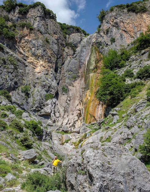 Mann telefoniert auf dem Hintergrund Wasserfall in der Athamanischen Bergregion Tzoumerka Griechenland