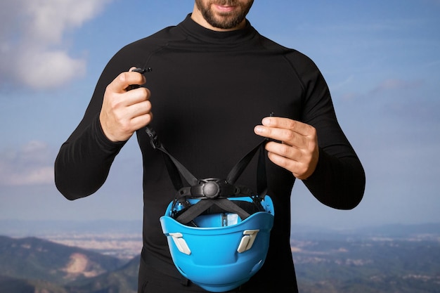 Mann touristischer Kletterer mit einem Helm einen Schutzhelm in seinen Händen in der Höhe der Berge
