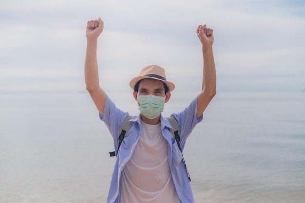 Mann trägt Gesichtsmaske mit Tasche reisen am Strand