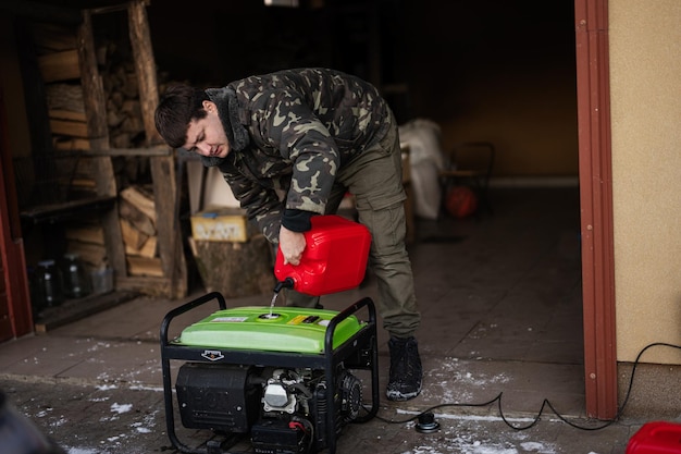 Mann trägt in Militärjacke Benzin aus Kanister in tragbaren mobilen Backup-Standby-Generator