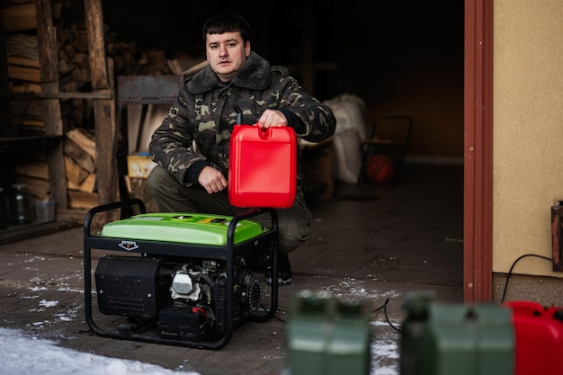 Mann trägt in Militärjacke Benzin aus Kanister in tragbaren mobilen Backup-Standby-Generator