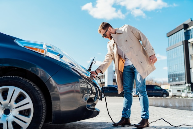 Mann trennt das Ladekabel von seinem Elektroauto