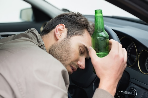 Mann trinkt Bier beim Autofahren