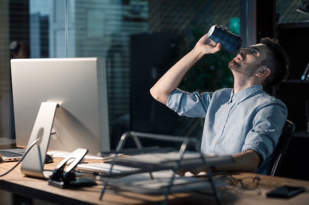 Mann trinkt Kaffee, der Stunden arbeitet