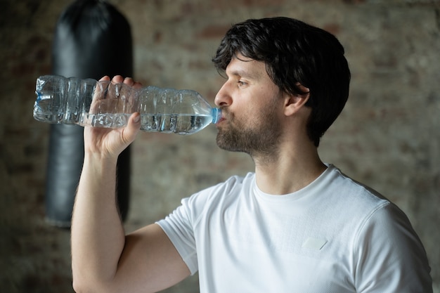 Mann trinkt Wasser von Flasche in der Turnhalle Gesundheitspflege und Training