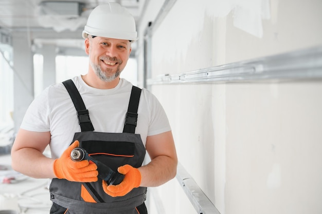 Mann, Trockenbauer, der Gipskartonplatten an der Wand installiert