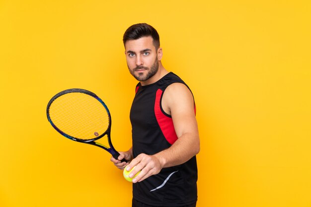 Mann über der lokalisierten gelben Wand, die Tennis spielt