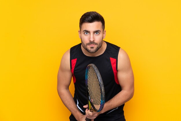 Mann über isolierter gelber Wand, die Tennis spielt