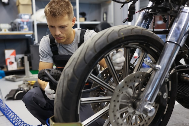 Mann überprüft den Reifendruck auf dem Motorrad im Werkstatt-Reifenservice-Konzept