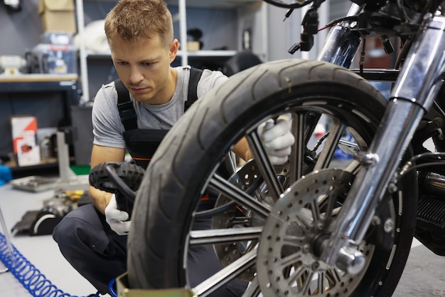 Mann überprüft den Reifendruck auf dem Motorrad im Werkstatt-Reifenservice-Konzept