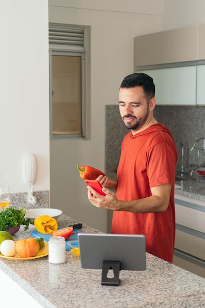 Mann überprüft sein Handy, während er zu Hause kocht